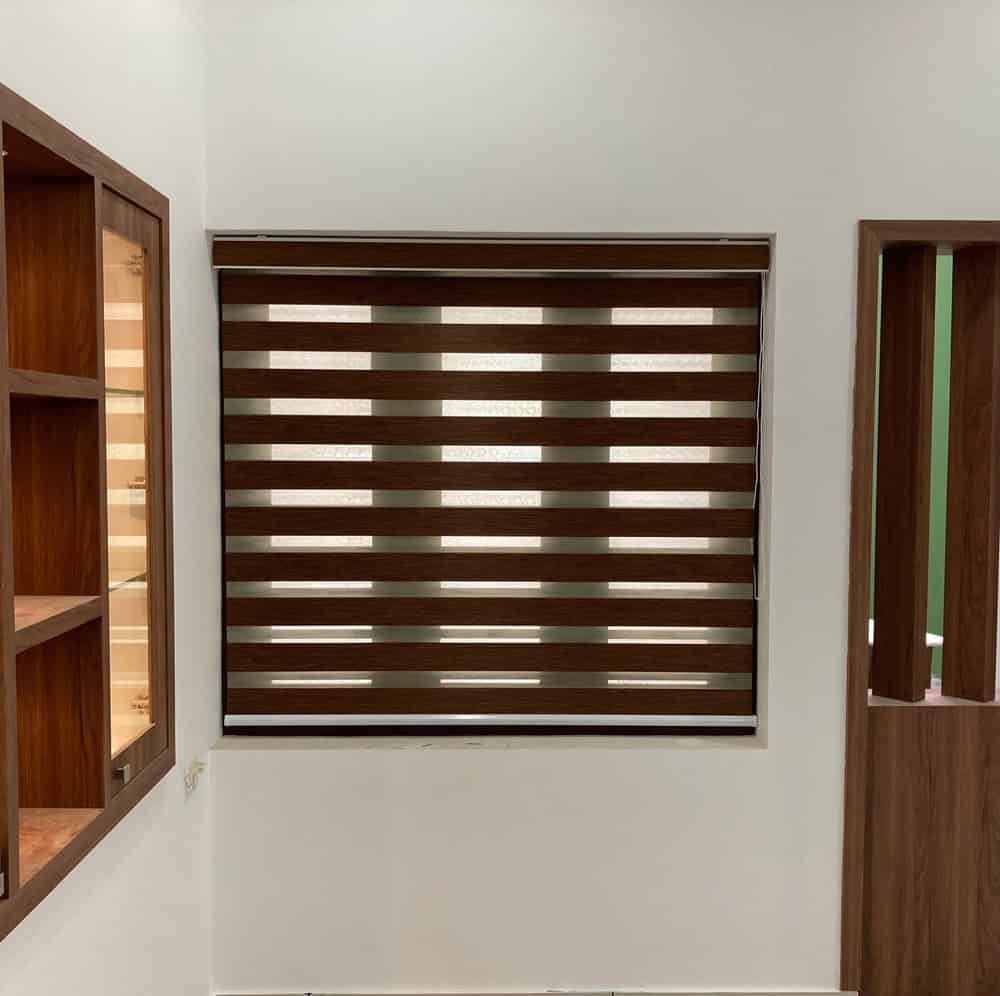 A modern room features a window with brown and beige horizontal striped blinds, flanked by wooden shelving on the left and a wooden partition on the right, all set against white walls.