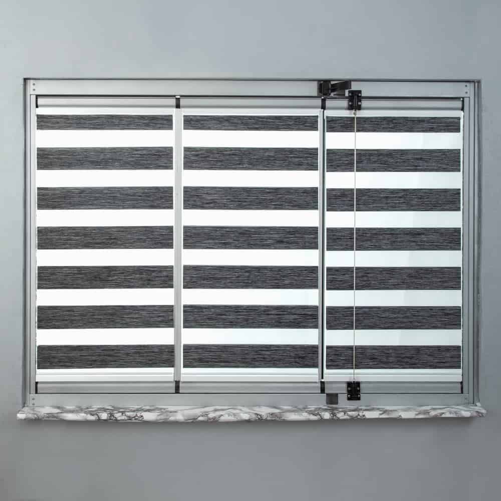 A glass window with a metal frame, featuring horizontal black and white striped blinds, is set in a light gray wall above a gray marble windowsill.