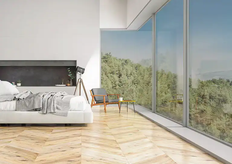 Spacious minimalist bedroom with large windows overlooking trees and mountains.