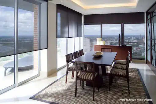 Dining room with modern furniture and floor-to-ceiling windows overlooking a cityscape.