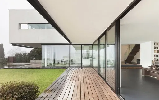 Modern minimalist home with glass walls and wooden deck.