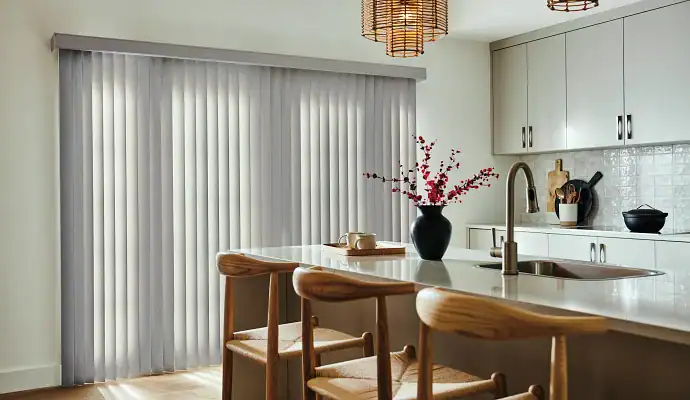 Modern kitchen with island, chairs, decor, and vertical blinds.