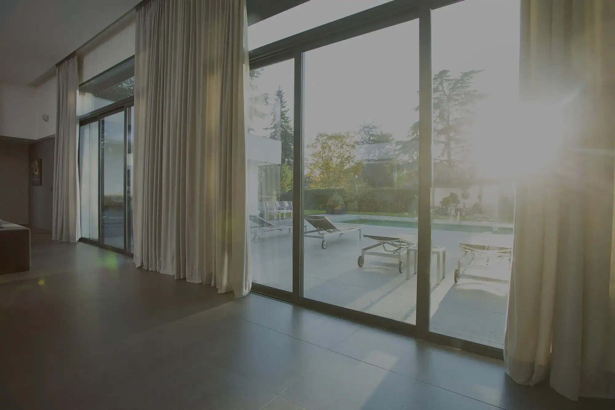 Spacious room with glass doors opening to a sunlit patio with loungers.