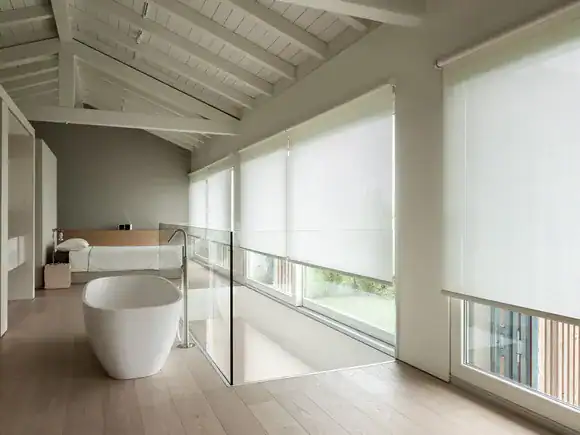 Spacious loft bathroom with freestanding tub and large windows.