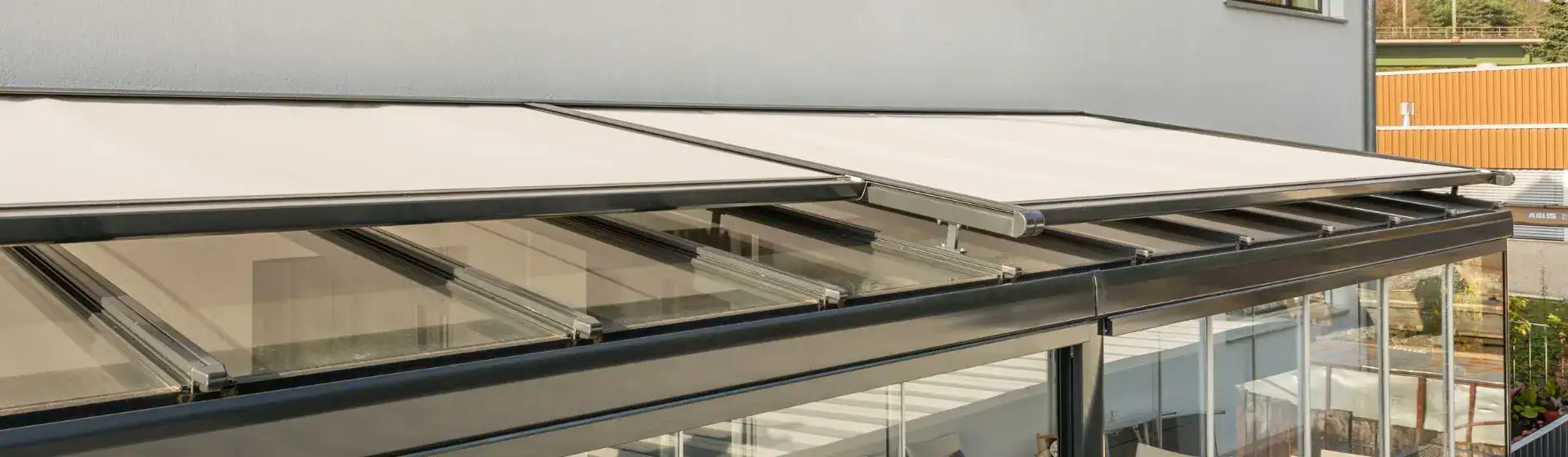 Retractable patio awning providing shade over glass enclosure.