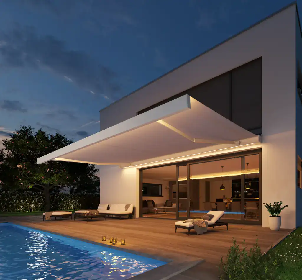 Modern home with a spacious patio and illuminated pool at night.