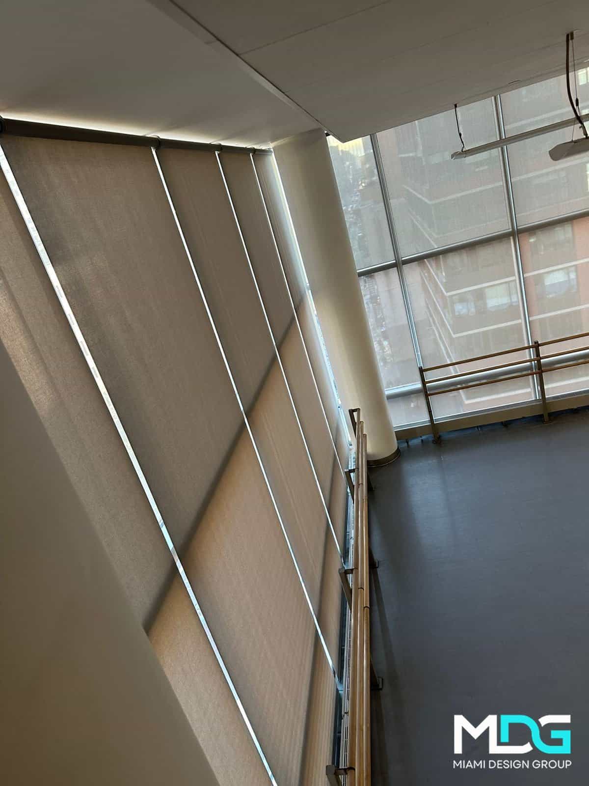 Large windows with beige roller shades and metal railings highlight MDG Miami Design Group’s luxury style.