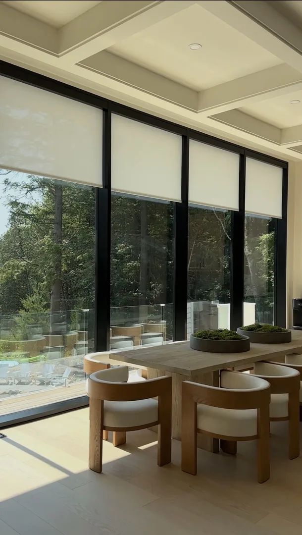 Closer view of the dining area beside tall windows with roller shades